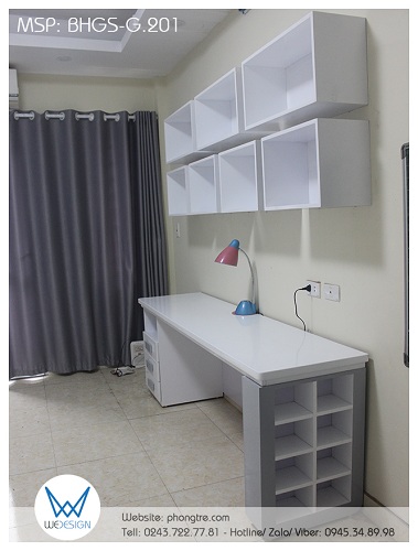 Bàn học đôi có giá sách treo tường kiểu hộc BHGS-G.201 được đặt ở tường bên phải của cửa ra vào phòng, đối diện với giường và có chiều ngang bằng giường
