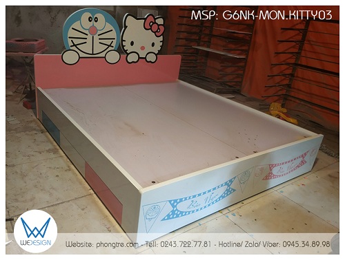 Đầu cao giường tạo hình Doraemon và Hello Kitty cùng giơ tay ra phía trước ôm lấy đầu cao giường màu hồng & đầu thấp thì trang trí cờ dây Doraemon và Hello Kitty có tên bé